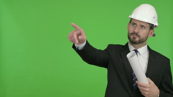 Engineer with Blueprint Pointing with Finger Against Chroma Key