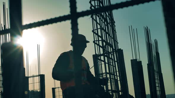 Builder Fixes Armature While Working on Construction Site.