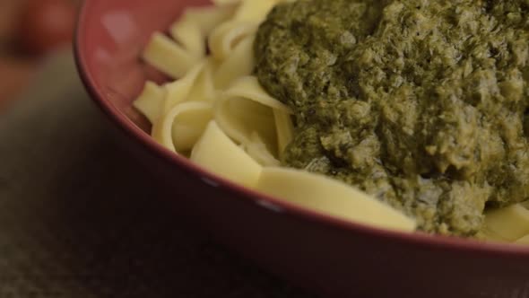 Serving of green pesto and tagliatelle pasta rotating macro shot