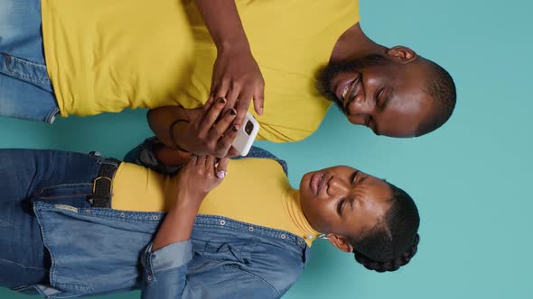 Vertical Video Modern Couple Looking at Mobile Phone Screen Together in Studio