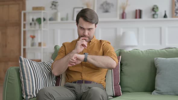 Young Man using Smart Watch while Sitting on Sofa