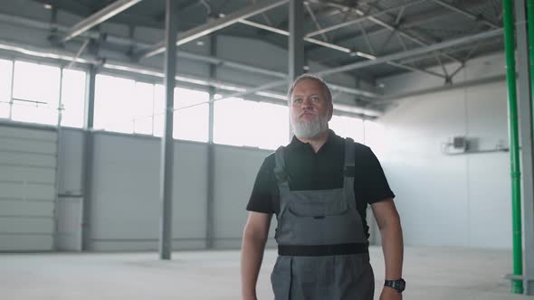 Portrait of Adult Grayhaired Man Worker Walks Through the Warehouse a Working Engineer Walks Through