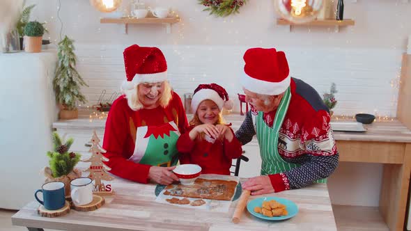 Funny Senior Grandparents and Granddaughter Playing with Flour Smearing on Face at Christmas Kitchen