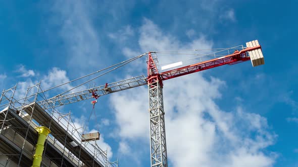 red tower crane with blue sky and clouds