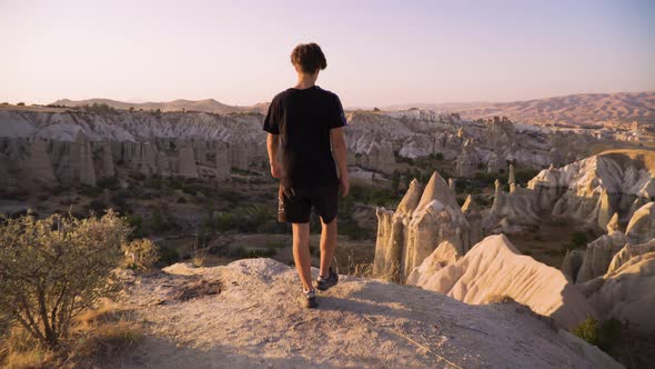 Young man walks towards a scenic viewpoint at sunset