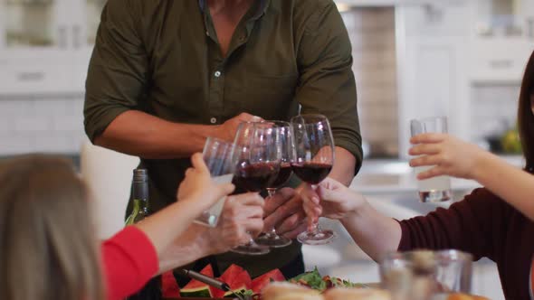 Smiling caucasian mother making a toast with multi-generation family at table before meal