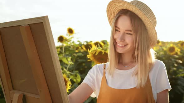 A Woman is Standing in a Field of Sunflowers and Drawing a Picture