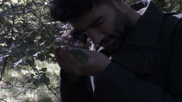 Male Botanist Using Handheld Loupe Magnifier On Leaf. Static Shot