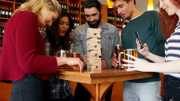 Group of fiends playing jenga while having beer 4k