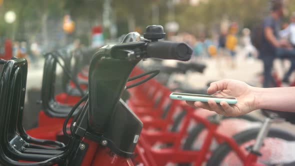 Woman Take Rent Electric Kick Scooter or Bike Bicycle in Sharing Parking Lot Tourist Phone