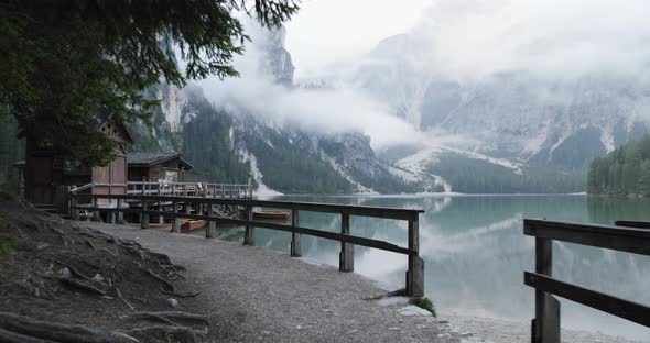 POV Walking to Boathouse with Wood Pier and Boats on Braies Lake in Cloudy Day