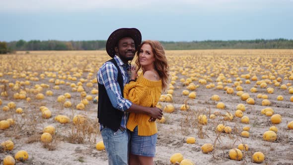 A Young Couple Stands Embracing in a Pumpkin Field