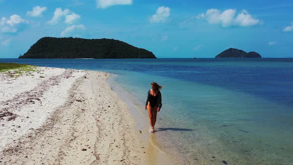 Sexy woman enjoying a summer holiday on the tropical island. Relaxing walk along the coast with whit