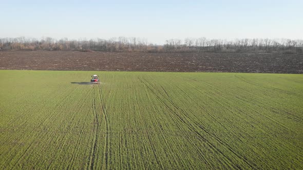 Tractor Spreading Artificial Fertilizers in Green Field