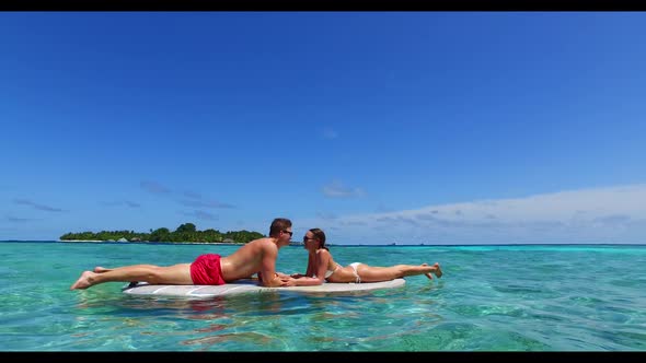 Guy and girl tan on tropical shore beach lifestyle by blue water with white sandy background of the 