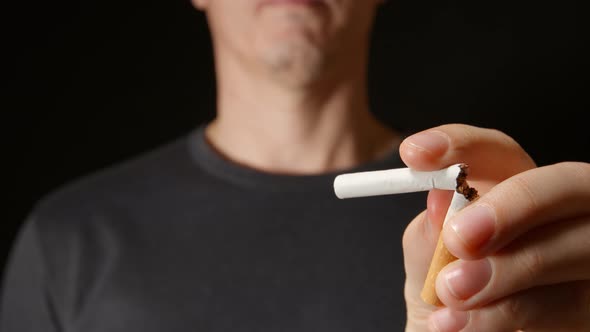 Young Adult Man Holds A Cigarette At One Hand And Then Break It