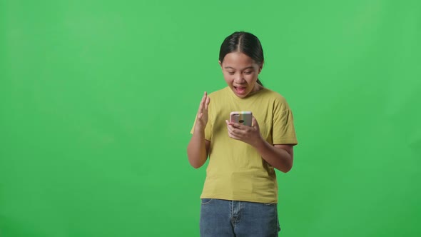 Young Asian Kid Girl Surprise And Say Wow During Use Mobile Phone While Standing On Green Screen