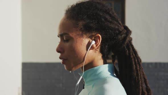 Portrait of african american woman in sportswear wearing earphones on a sunny day