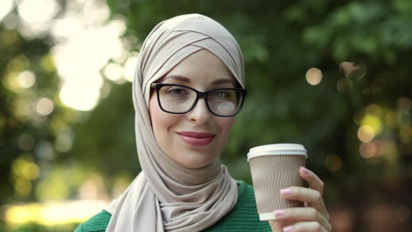 Attractive Smiling Muslim Woman in Hijab Holding Cup of Coffee