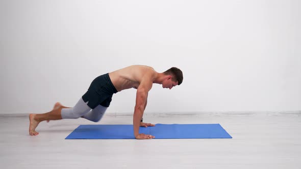 Muscular Sportsman Doing Mountain Climber Exercise on Fitness Mat Warmup
