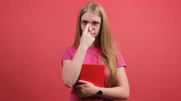 Positive Girl Sitting with a Notebook in Her Hand and Straightening Her Glasses.