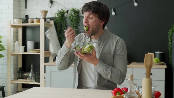 Man in Shirt Eating Salad in the Kitchen