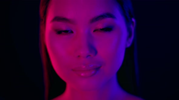 Blurred Closeup Portrait Of Young Beautiful Asian Woman Standing Under Neon Lighting