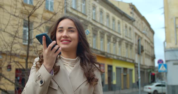 Woman Using a Smartphone Voice Recording Function Online in the City Street, Voice Message. Girl