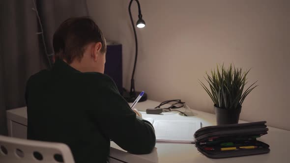 back view of 7 year old boy doing homework at home