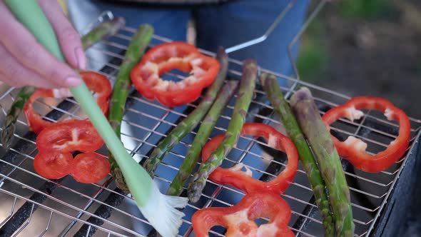 Making Grilled Vegetables Brushing Oil on Asparagus and Red Pepper on a Charcoal Grill