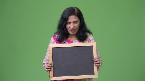 Mature Happy Beautiful Indian Woman Looking Surprised While Showing Blackboard