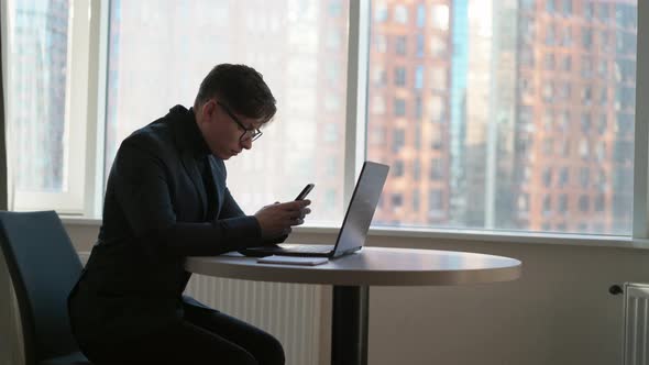 Smiling Young Businessman Holding Smartphone Sitting in Office Ceo 25 Years Old Wearing Glasses