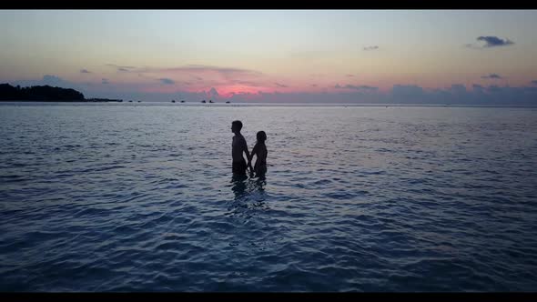 Man and woman tanning on idyllic sea view beach lifestyle by shallow ocean and white sand background