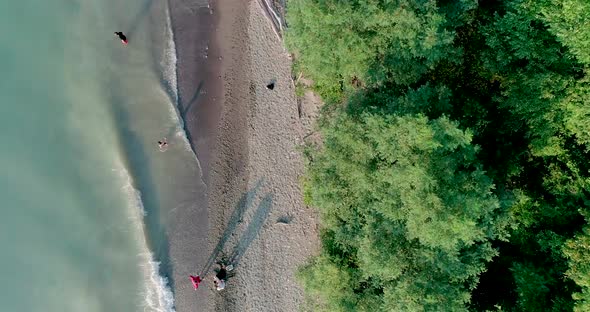 Overhead Aerial Shot of a lakeshore with various people along the shore enjoying a hot summer day wi