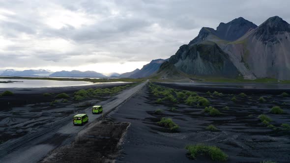 Aerial View Of Two Vans Driving Towards The Famous Vestrahorn Mountain In Iceland. - follow