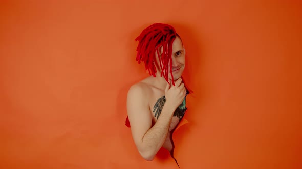 Portrait of a Handsome Shirtless Man with Red Dreadlocks and a Tattoo of a Bird on His Chest Looking