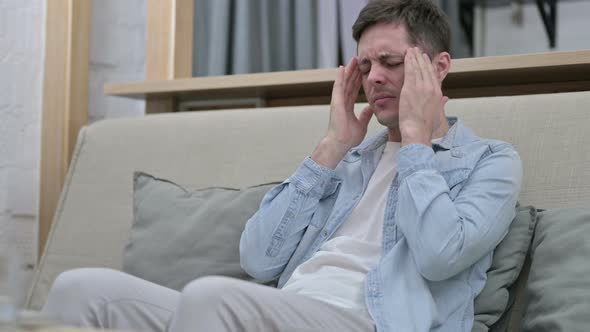 Stressed Young Man Having Headache in Living Room 