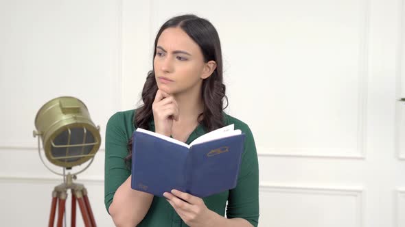 Thoughful Indian woman reading a book