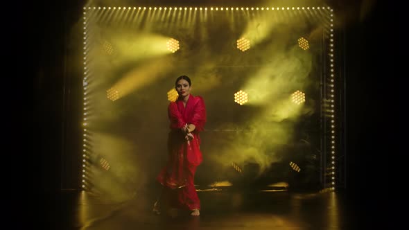 Young Girl Dancer in a Red Sari. Indian Folk Dance. Shot in a Dark Studio with Smoke and Yellow Neon