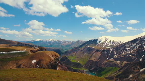 Panoramic View of Kazbegi Mountains and the Green Valley Crossed with Roads and with a Blue Lake