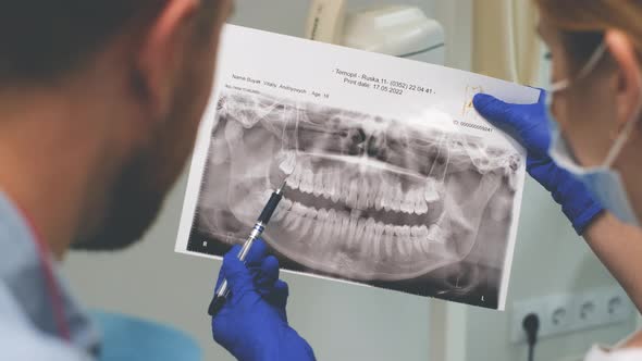 Female Doctor Shows the Patient an Xray of the Teeth