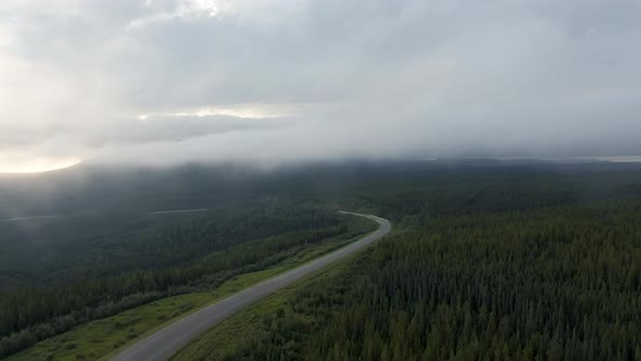 Beautiful View of Scenic Road From Above Surrounded By Lush Forest, Clouds and Mountains