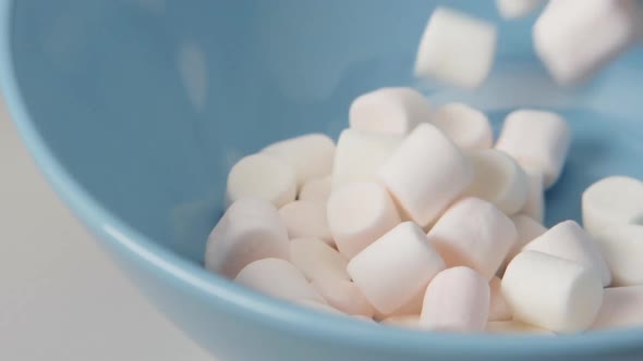 Marshmallows fall on blue dish