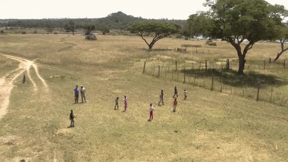 Aerial is showing african kids playing football on a field at Imire, Zimbabwe