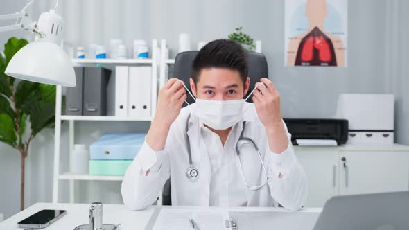 Portrait of Asian male doctor remove protective face mask in hospital.