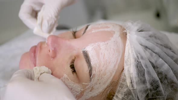 Doctor Beautician Removes White Cream From the Face of His Patient Lying