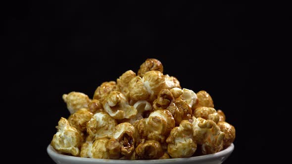 Coffee taste popcorns rotating into the bowl on black background close up. Caramel popcorn. Health