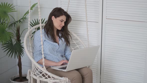 Portrait of a Self-employed Woman Working at Home. Girl Freelancer Sits in a Comfortable Hanging