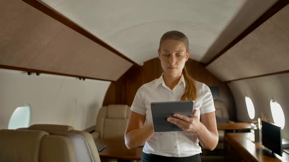 Businesswoman in Air Private Jet Surfing Internet on Digital Pad