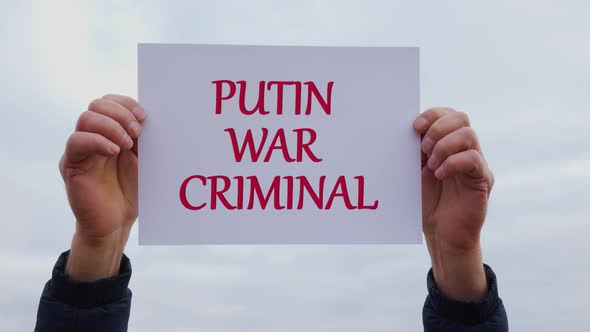 Man Hands Holding Piece of White Cardboard with Words Putin Ear Criminal